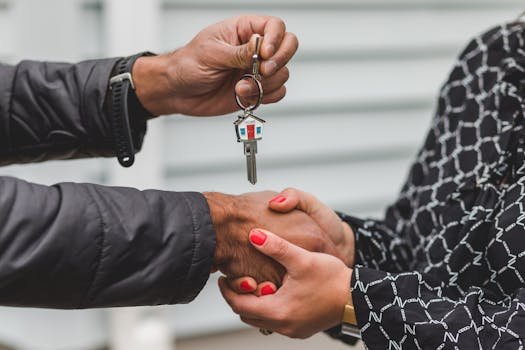 pexels-photo-8293778-8293778 Close-up of a realtor handing over a house key to a new homeowner, symbolizing ownership and investment.